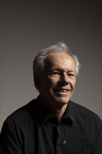 Studio portrait of smiling senior man in black shirt against gray background, Bellevue, Idaho, USA