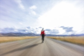 Rear view of woman walking on rural road, blurred motion, Bellevue, Idaho, USA