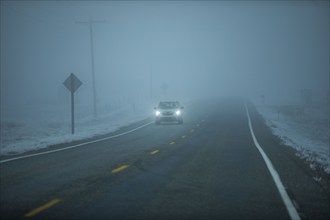 Car on Idaho 20 road in heavy fog at dusk, Mountain Home, Idaho, USA