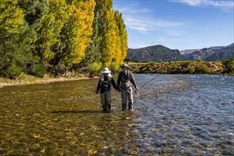 Rear view of senior couple flyfishers wading in Traful River, Estancia Arroyo Verde, Nequen