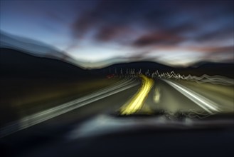 Blurred rural highway seen from moving car at dusk, Buttonwillow, California, USA