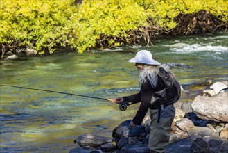 Woman in white hat fly fishing on Traful River, Estancia Arroyo Verde, Nequen Province, Argentina