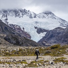 Argentina, Santa Cruz, El Chalten, Rear view of female hiker crossing rocky bed of Electrico River,