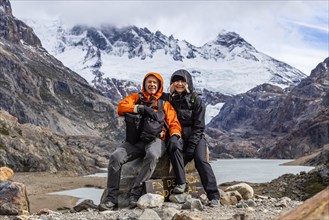 Argentina, Santa Cruz, El Chalten, Portrait of smiling hikers sitting at trails end below Marconi