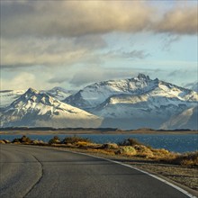 Argentina, Santa Cruz, El Calafate, Empty road with lake and snowcapped mountains in background, El