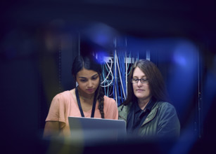 Two female technicians using laptop in server room 
St, George, Utah, USA