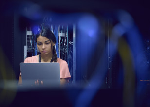 Female technician using laptop in server room 
St, George, Utah, USA