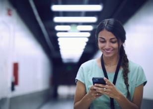 Smiling female technician looking at smart phone in server room 
St, George, Utah, USA