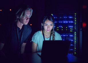 Female and male technicians using laptop in server room 
St, George, Utah, USA