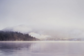 Morning mist rising over calm Lake Placid 
St. Armand, New York, USA