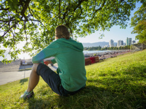 Rear view of woman sitting on lawn near coast
Vancouver, British Columbia, Canada