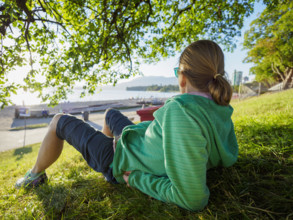 Rear view of woman sitting on lawn near coast
Vancouver, British Columbia, Canada