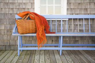 Picnic basket and orange blanket on blue wooden bench outside cottage house
Nantucket,