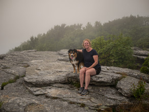 Portrait of smiling woman with Black Tri Australian Shepard sitting on rocks
Blacksburg, Virginia,