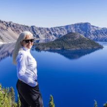 USA, Oregon, Portrait of smiling woman near calm Crater lake