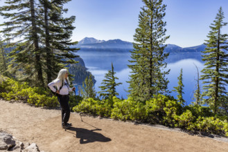 USA, Oregon, Smiling woman with hiking poles on footpath near calm Crater lake