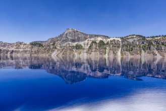 USA, Oregon, Cliffs reflected in calm surface of Crater lake