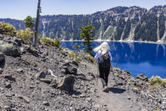 USA, Oregon, Rear view of woman hiking near calm Crater lake