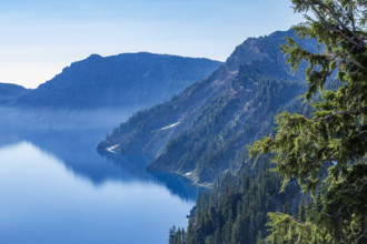 USA, Oregon, Hills reflected in calm, blue Crater lake
