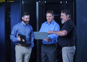 Workers looking at laptop in data center