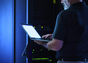 Close-up of man using laptop in data center
