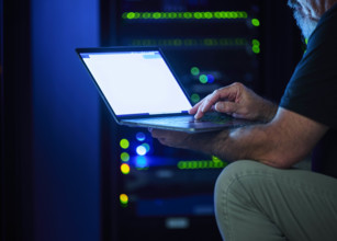 Close-up of man using laptop in data center