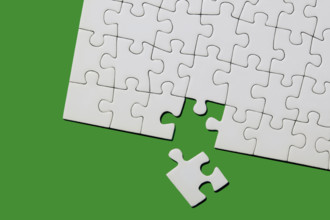 Studio shot of white puzzle pieces on green background