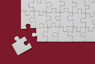 Studio shot of white puzzle pieces on red background