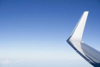 Jet airplane wing against clear blue sky