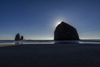 USA, Oregon, Sun setting behind haystack rock on Cannon Beach