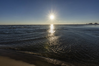 USA, Oregon, Sun setting over ocean and empty Cannon Beach