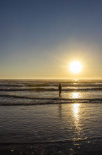 USA, Oregon, Cannon Beach, Woman standing in ocean at sunset