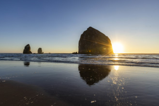 USA, Oregon, Sun setting behind haystack rock on Cannon Beach
