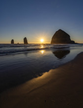USA, Oregon, Sun setting behind haystack rock on Cannon Beach