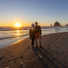 USA, Oregon, Cannon Beach, Portrait of smiling senior couple on beach with haystack rock in
