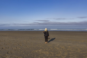 USA, Oregon, Newport, Rear view of woman standing on empty beach