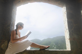 USA, United States Virgin Islands, St. John, Young woman reading in window of villa