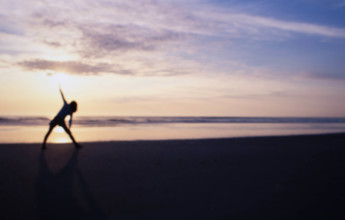 USA, New Jersey, Spring Lake, Defocussed image of woman athlete stretching on beach