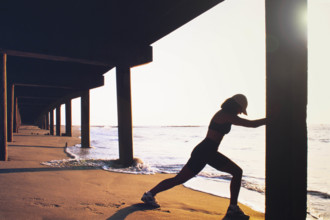 USA, New Jersey, Spring Lake, Female athlete stretching on beach before running