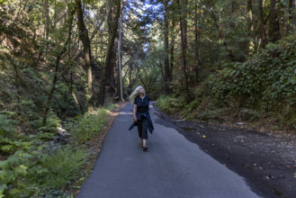 USA, California, Mill Valley, Woman walking on paved pathway in forest