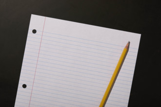 Lined paper and pencil on black background