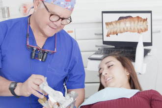 Dentist explaining dental hygiene to patient using jaw model