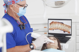 Dentist scanning female patients teeth with 3D scanner