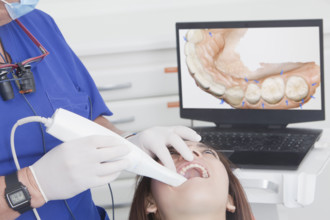 Dentist scanning female patients teeth with 3D scanner