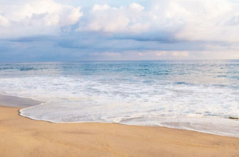 Mexico, Oaxaca State, Puerto Escondido, Costa Chica, Cumulus clouds over ocean waves on empty beach