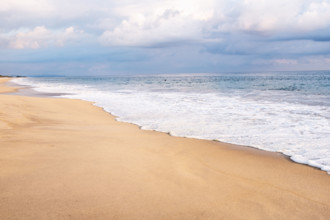 Mexico, Oaxaca State, Puerto Escondido, Costa Chica, Clouds overs ocean waves on empty beach