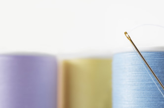 Studio shot of needle and colorful spools of threads