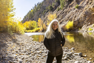 USA, Idaho, Bellevue, Portrait of senior blonde woman at river in autumn