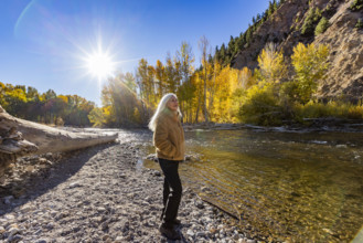 USA, Idaho, Hailey, Senior blonde woman at river in autumn