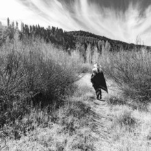 USA, Idaho, Sun Valley, Rear view of woman in wool poncho on footpath in landscape